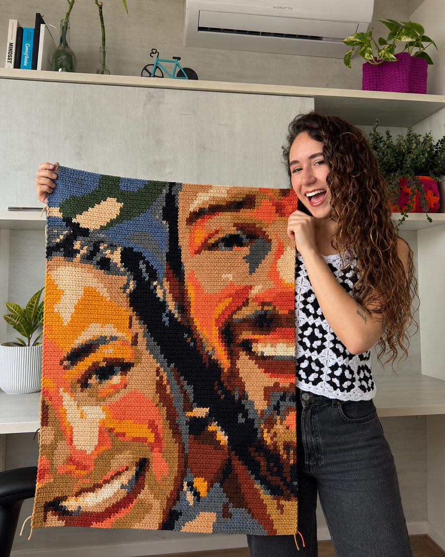 Girré sosteniendo una pieza grande de pintura en crochet